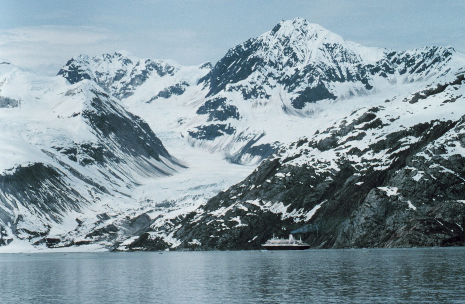 A cruise ship beneath snowcapped mountains in Glacier Bay, Alaska